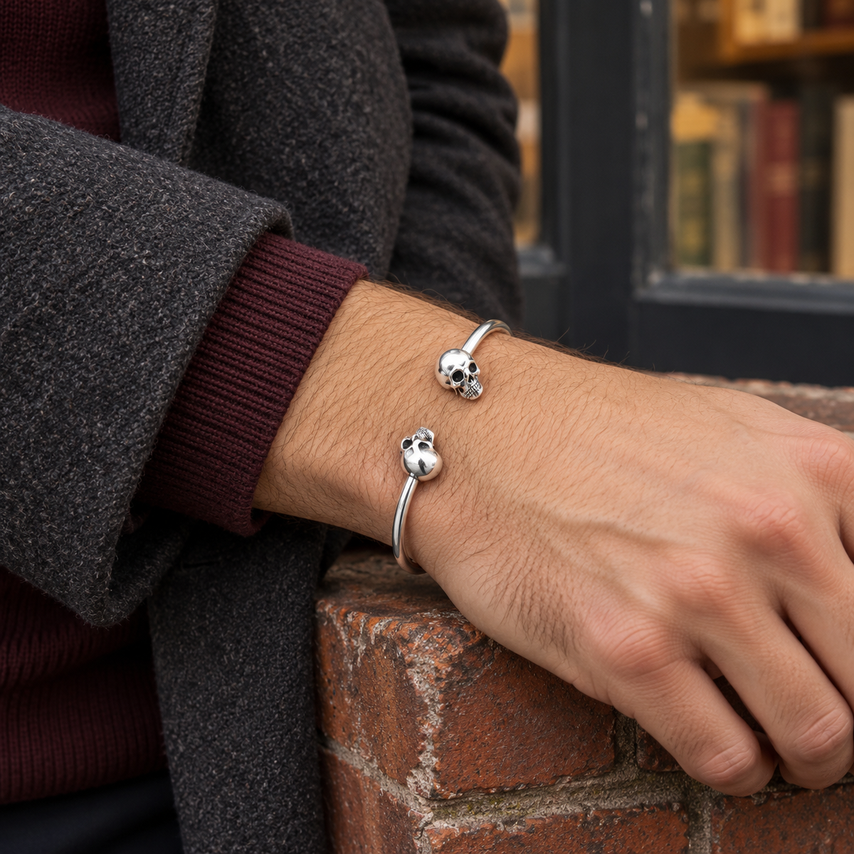 Men's Smooth Twin Skull Cuff in Sterling Silver – contextual scene, on wrist with burgundy knitwear and a charcoal wool coat
