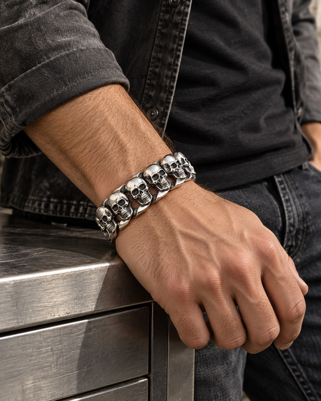 Men's Skull Curb Sterling Silver Bracelet in Sterling Silver – contextual scene, on wrist with charcoal suede at a workshop cabinet