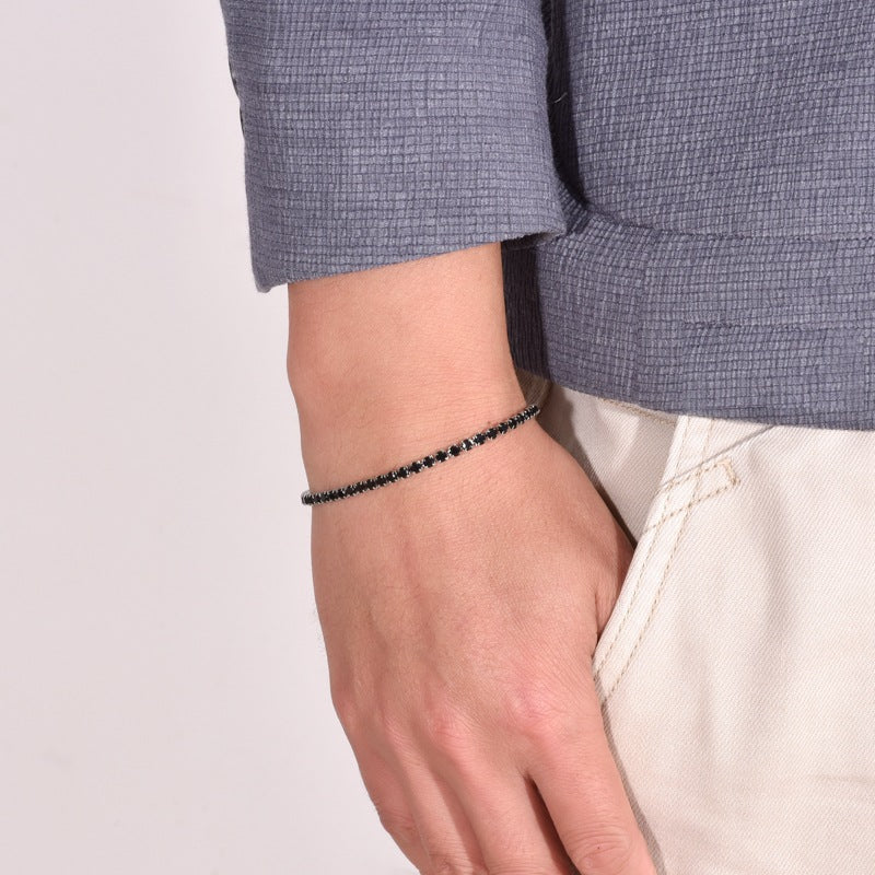 Men's Round Light Tennis Bracelet in Black Zirconia / Silver-Tone Steel – contextual scene, on wrist with a blue-grey blazer and cream trousers