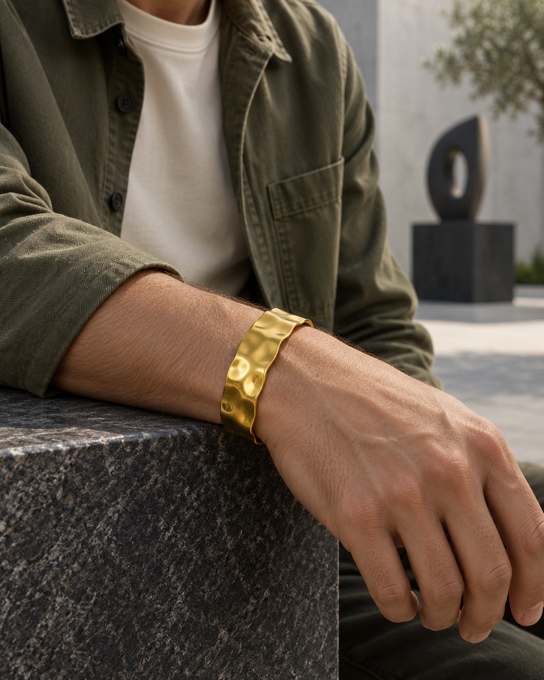 Men's Molten Hammered Cuff in gold-tone 18K Gold Plated Steel – contextual scene, on wrist in an art courtyard