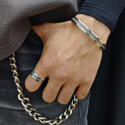 Men's Riven Texture Cuff in Sterling Silver – contextual scene, on wrist with a navy sleeve and dark denim