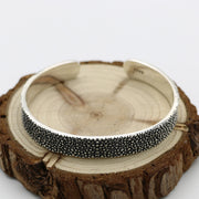 Men's Granular Texture Cuff in Sterling Silver – original textured band on a wooden display
