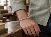 Men's Quill Line Cuff in Sterling Silver – contextual scene, on wrist in a bookshop