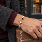 Men's Smooth Twin Skull Cuff in Sterling Silver – contextual scene, on wrist with burgundy knitwear and a charcoal wool coat
