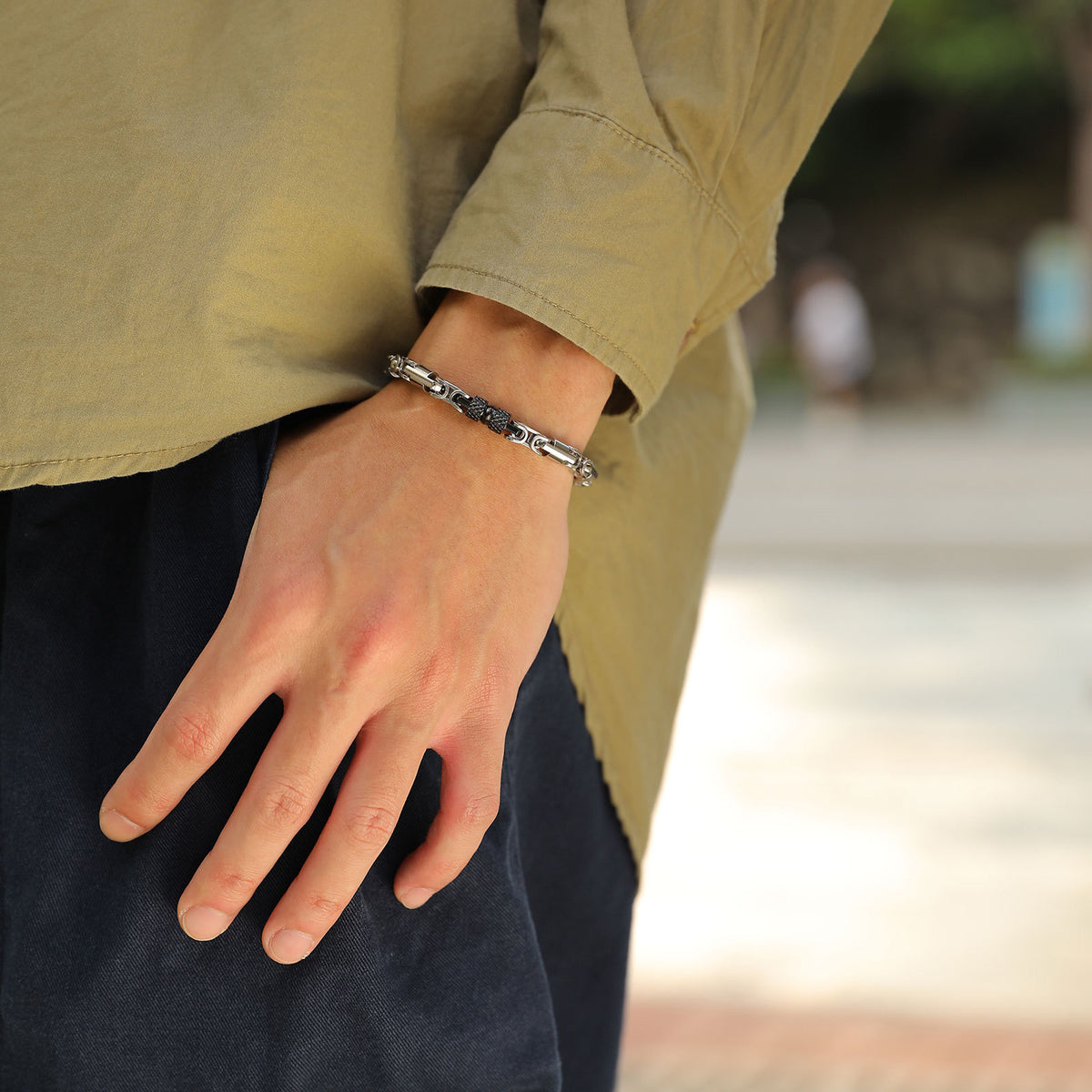 Men's Knurled Byzantine Bracelet in black and silver-tone stainless steel – contextual scene on wrist with an olive overshirt and dark trousers