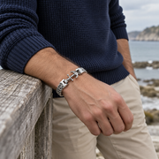 Men's Anchor Chevron Bracelet in Silver-Tone Stainless Steel – contextual scene, on wrist beside a coastal railing