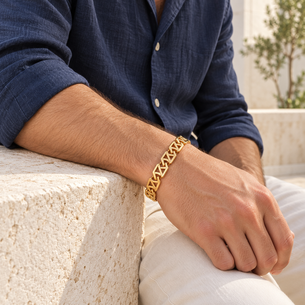 Men's Diagonal Open Link Bracelet in 18K Gold Plated Steel – contextual scene, on wrist with navy linen and cream trousers